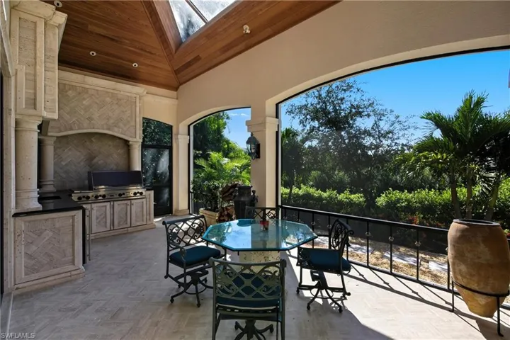 View of patio with exterior kitchen, outdoor dining space, and a sunroom