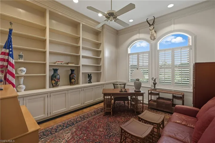 Office featuring built in features, crown molding, ceiling fan, and dark wood-style floors