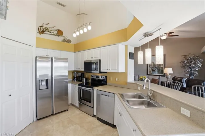 Stainless steel appliances, white wood cabinetry, and bright finishes make this kitchen POP!