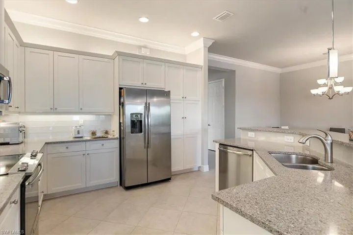 Kitchen featuring white cabinetry, appliances with stainless steel finishes, sink, and decorative light fixtures