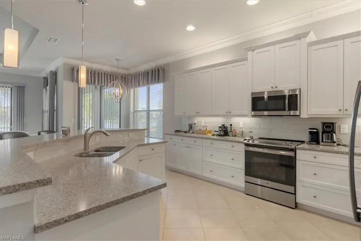 Kitchen featuring pendant lighting, sink, stainless steel appliances, and white cabinets