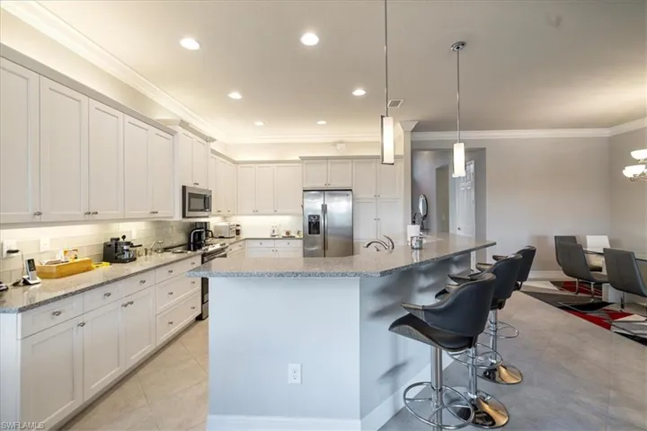 Kitchen featuring a kitchen island with sink, pendant lighting, stainless steel appliances, and white cabinets