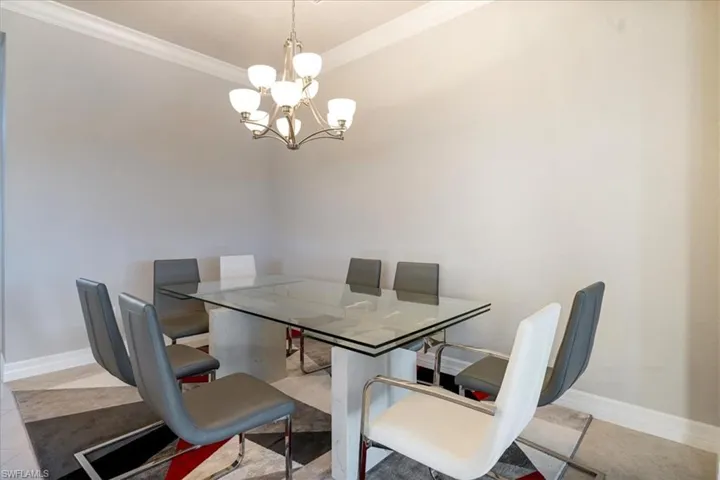 Tiled dining room with ornamental molding and an inviting chandelier