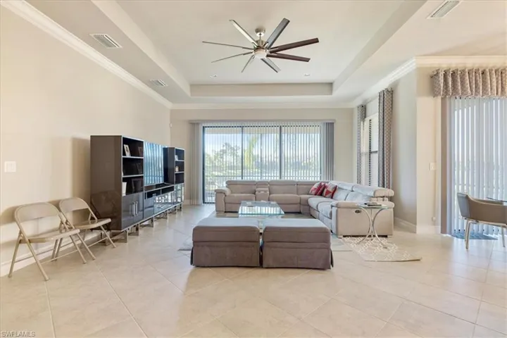 Tiled living room with a tray ceiling and ceiling fan