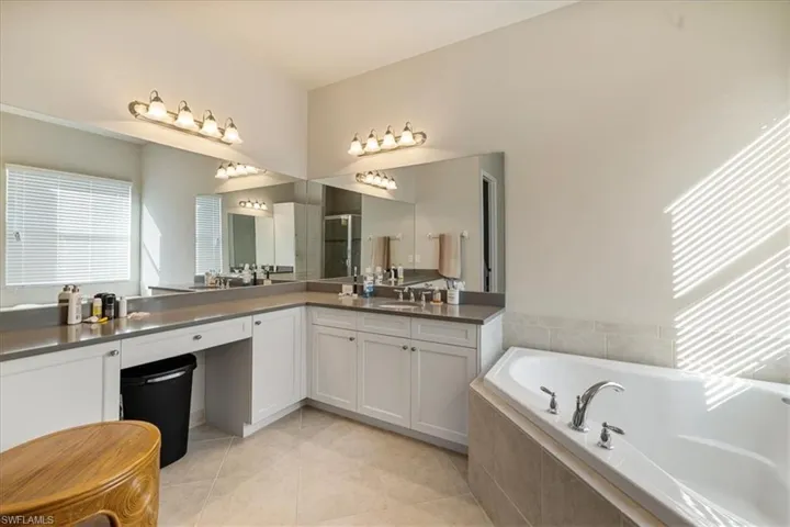 Bathroom with vanity, tile patterned floors, and plus walk in shower