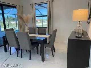 Dining space featuring light marble finish floors and baseboards