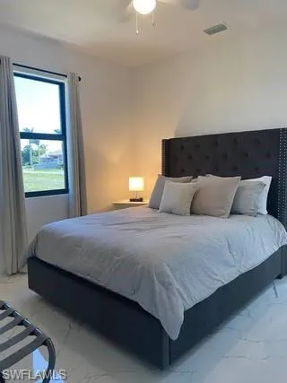Bedroom featuring light marble finish flooring and a ceiling fan