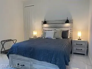 Bedroom featuring marble look tile flooring and baseboards