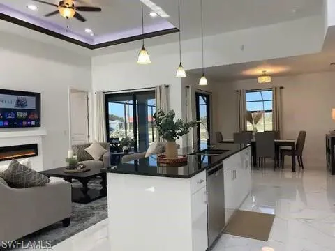 Kitchen featuring light marble finish floors, open floor plan, healthy amount of natural light, a raised ceiling, and recessed lighting