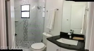 Full bathroom featuring a marble finish shower and vanity