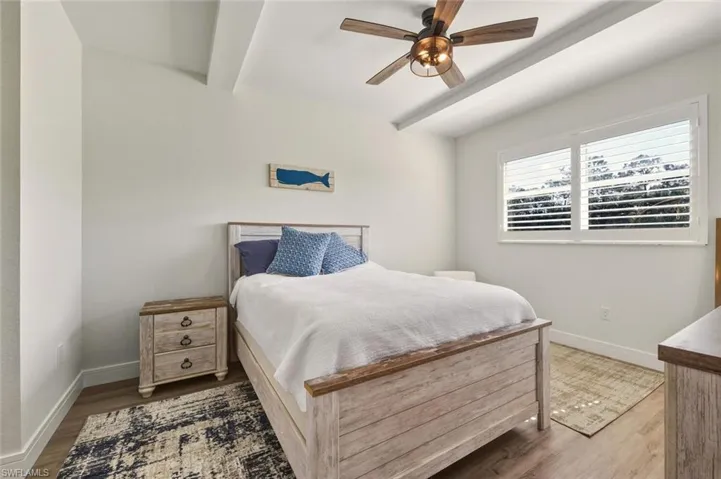 Bedroom featuring wood finished floors, beamed ceiling, and ceiling fan