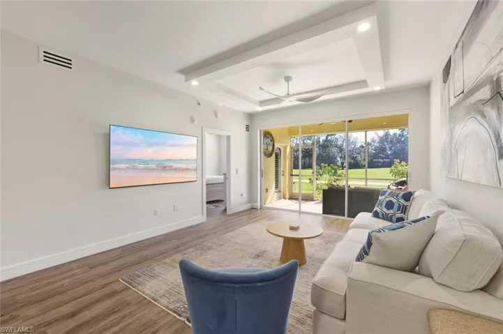 Living area with a tray ceiling, wood finished floors, a ceiling fan, and recessed lighting