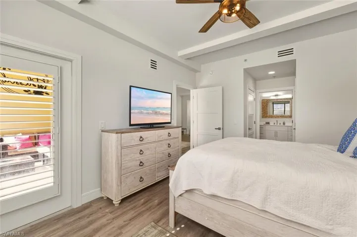 Bedroom with light wood-type flooring, a ceiling fan, access to exterior, and ensuite bathroom