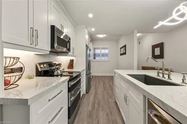 Kitchen with stainless steel appliances, pompei quartz countertops, white cabinets, and vinyl plank flooring