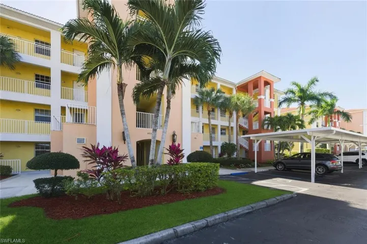 View of apartment building / complex featuring covered parking