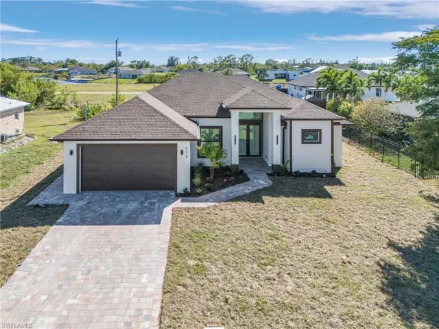 View of front of property featuring decorative driveway, fence, an attached garage, a shingled roof, and a front yard