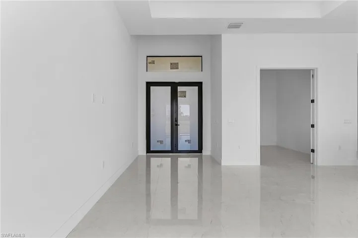 Spare room featuring marble finish floor, french doors, and baseboards