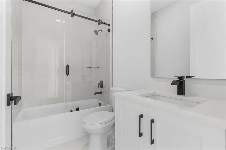 Full bathroom with toilet, vanity, and bath / shower combo with glass door