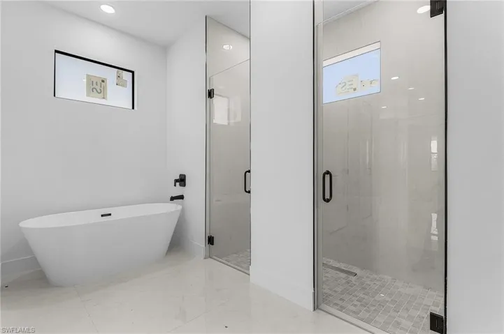 Bathroom with baseboards, a freestanding bath, marble finish floor, and a stall shower