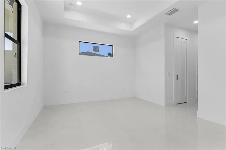 Spare room featuring visible vents, baseboards, a tray ceiling, recessed lighting, and marble finish floor