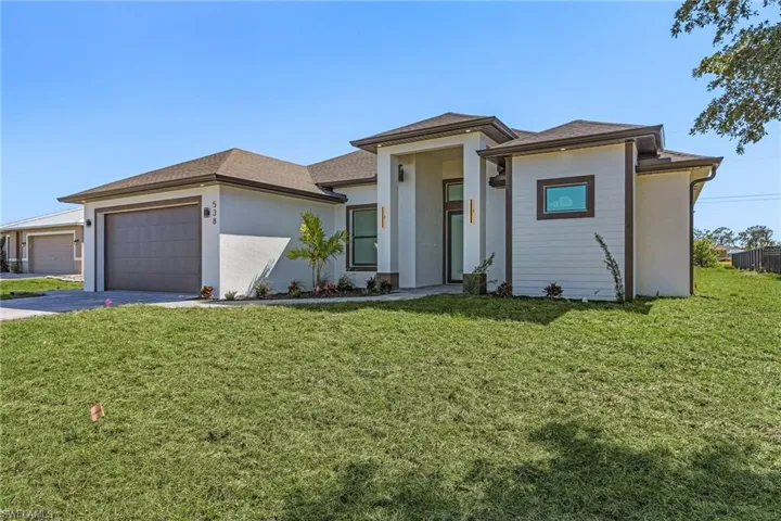 Prairie-style house with a front lawn, concrete driveway, a garage, and stucco siding