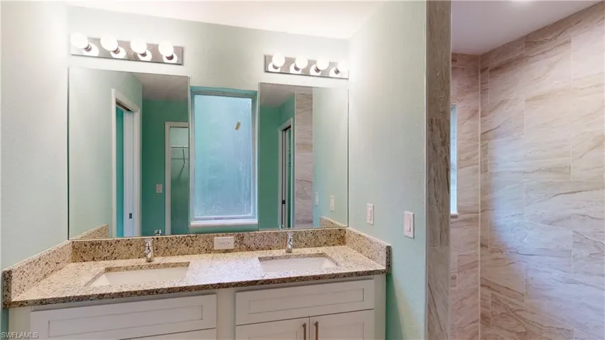 Bathroom featuring double vanity and a textured wall