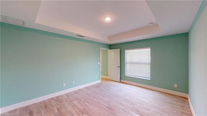 Empty room featuring a tray ceiling and light wood finished floors