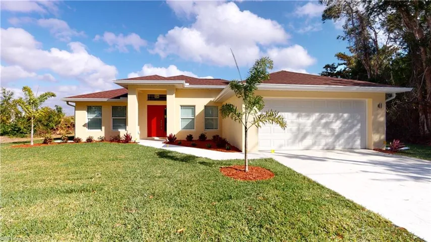 View of front facade featuring a front yard, stucco siding, concrete driveway, and an attached garage