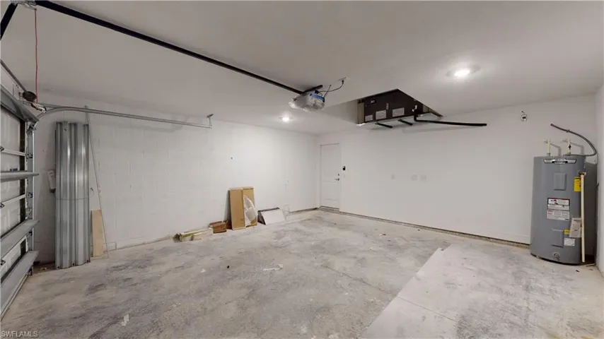 Garage with water heater, concrete block wall, and a garage door opener