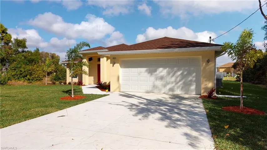 View of front of property with a front lawn, stucco siding, driveway, and a garage