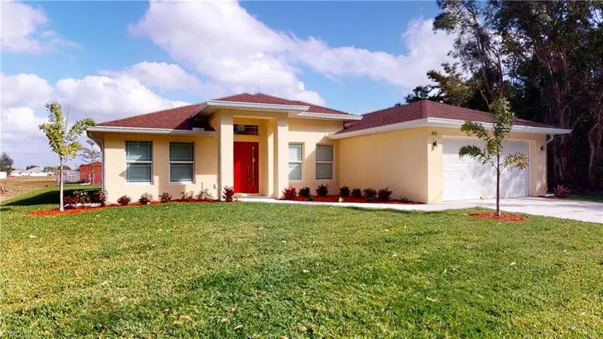 View of front of house with a front yard, stucco siding, an attached garage, and concrete driveway