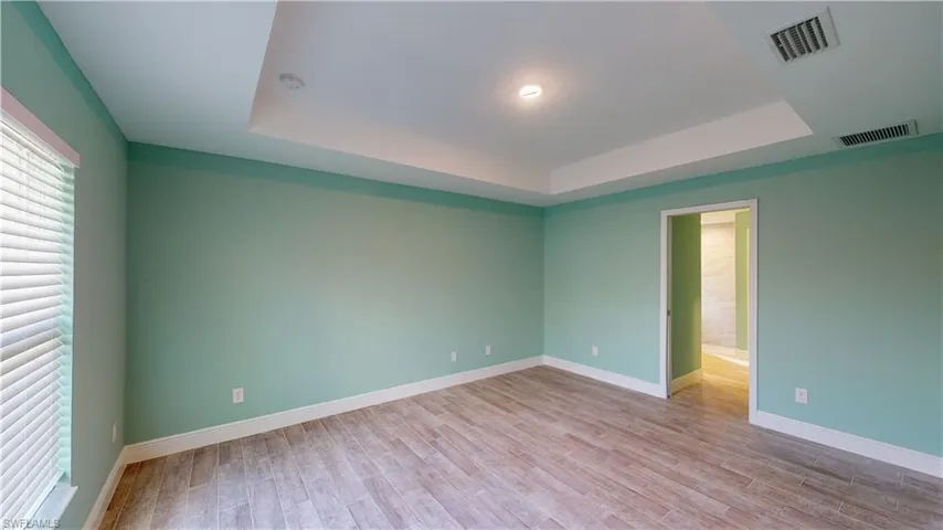 Unfurnished room with light wood-type flooring and a raised ceiling