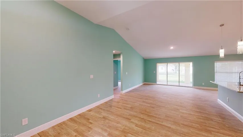Unfurnished living room featuring light wood-type flooring and lofted ceiling