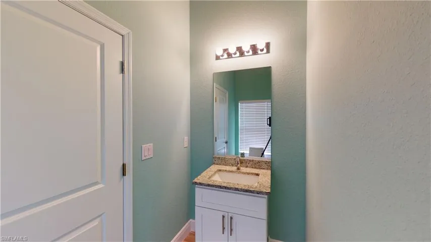 Half bath featuring vanity and a textured wall