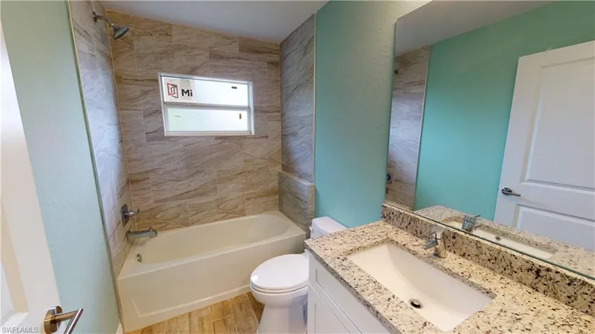 Bathroom featuring bathing tub / shower combination, vanity, light wood-style flooring, and a textured wall