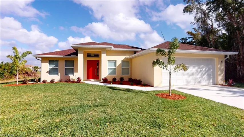 View of front of home with stucco siding, a front yard, and driveway