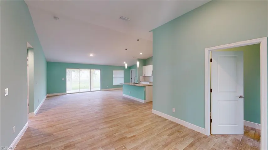 Unfurnished living room featuring light wood-style flooring, lofted ceiling, and recessed lighting