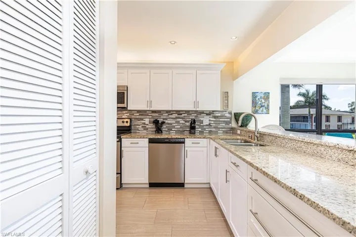 Kitchen featuring white cabinets, utility drawers, tasteful backsplash, granite countertops, sink, and stainless-steel appliances, pantry