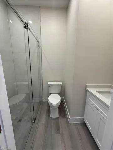 Full bath with a stall shower, vanity, and dark wood-style flooring