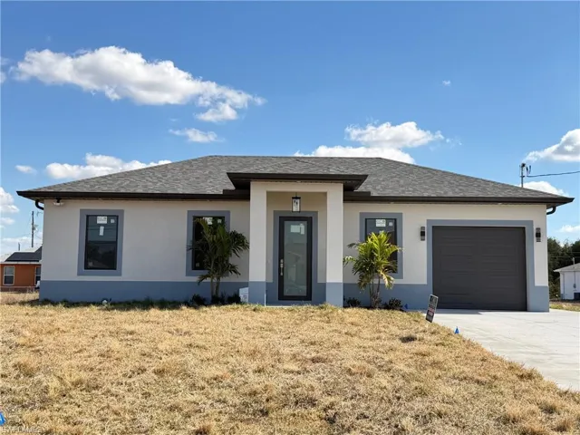 View of front of house featuring stucco siding, roof with shingles, a garage, driveway, and a front yard