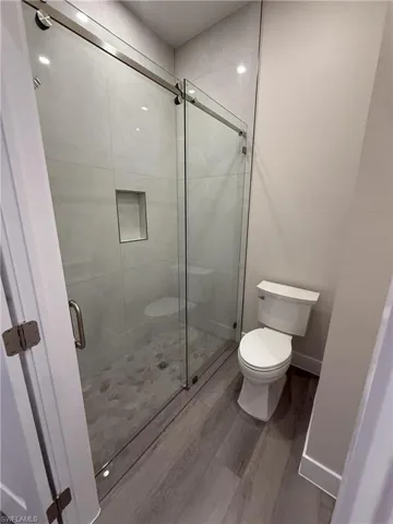 Full bath featuring wood finished floors and a stall shower