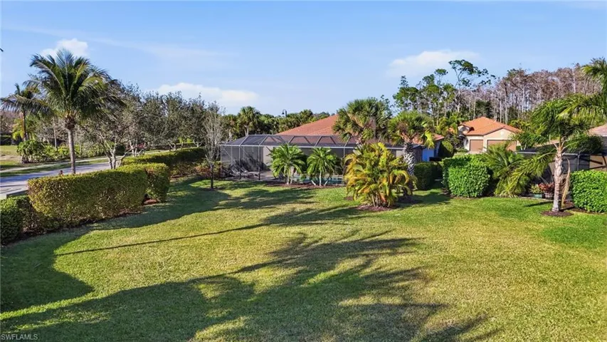 View of grassy yard featuring glass enclosure and a sunroom