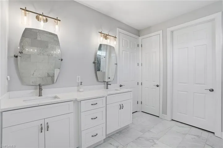 Bathroom featuring double vanity and light marble finish floors