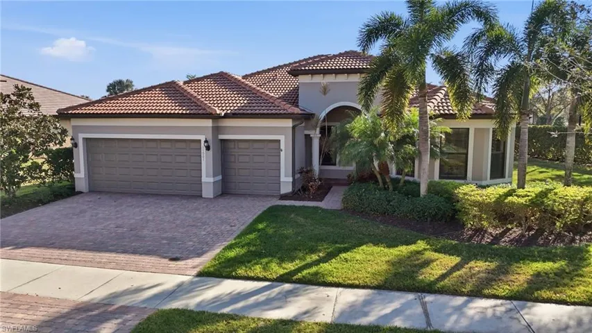 Mediterranean / spanish home featuring stucco siding, a garage, driveway, and a front lawn