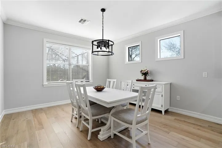 Dining room featuring light wood-style floors, crown molding, and a chandelier