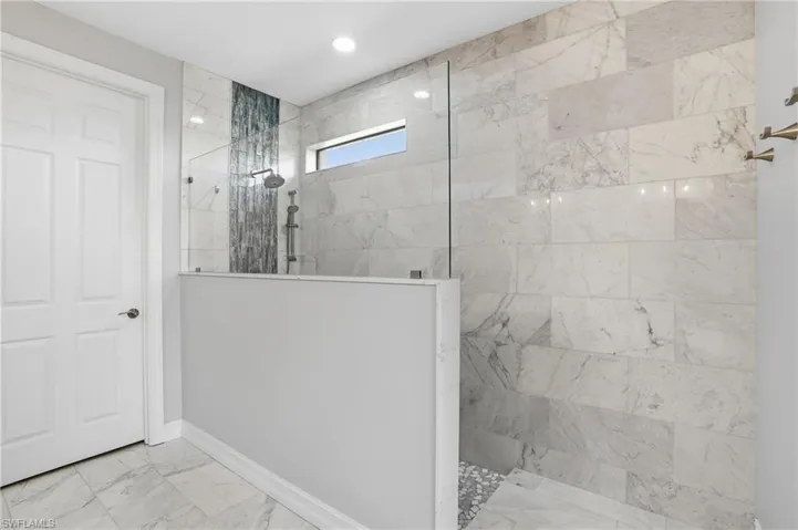 Full bathroom with walk in shower and marble look tiles