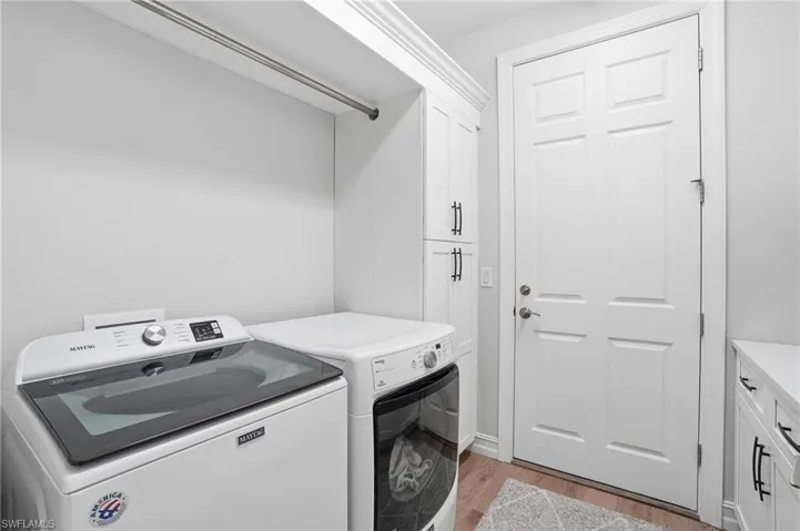 Laundry room featuring cabinet space, light wood-style flooring, and independent washer and dryer
