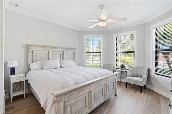 Bedroom with crown molding, light wood-style flooring, multiple windows, and a ceiling fan