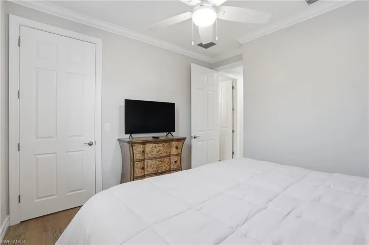 Bedroom featuring ornamental molding, wood finished floors, and a ceiling fan