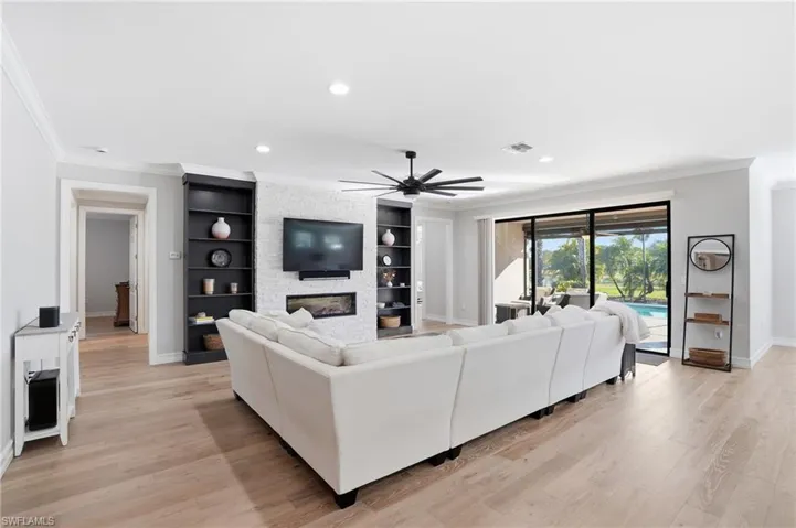 Living room with crown molding, ceiling fan, light wood-style floors, recessed lighting, and a fireplace